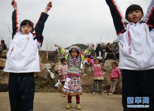 一名苗寨小学的苗族小朋友（中）跟着两位棠外来的姐姐跳现代舞